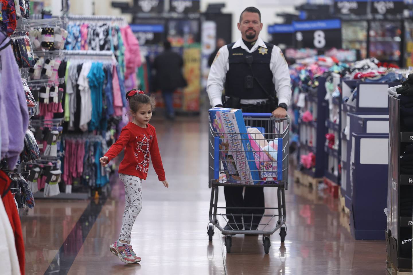 Lily, 6, dances down the aisle as she shops with Sgt. Kevin Sepulveda at the annual Santa Cop at Walmart in Joliet.