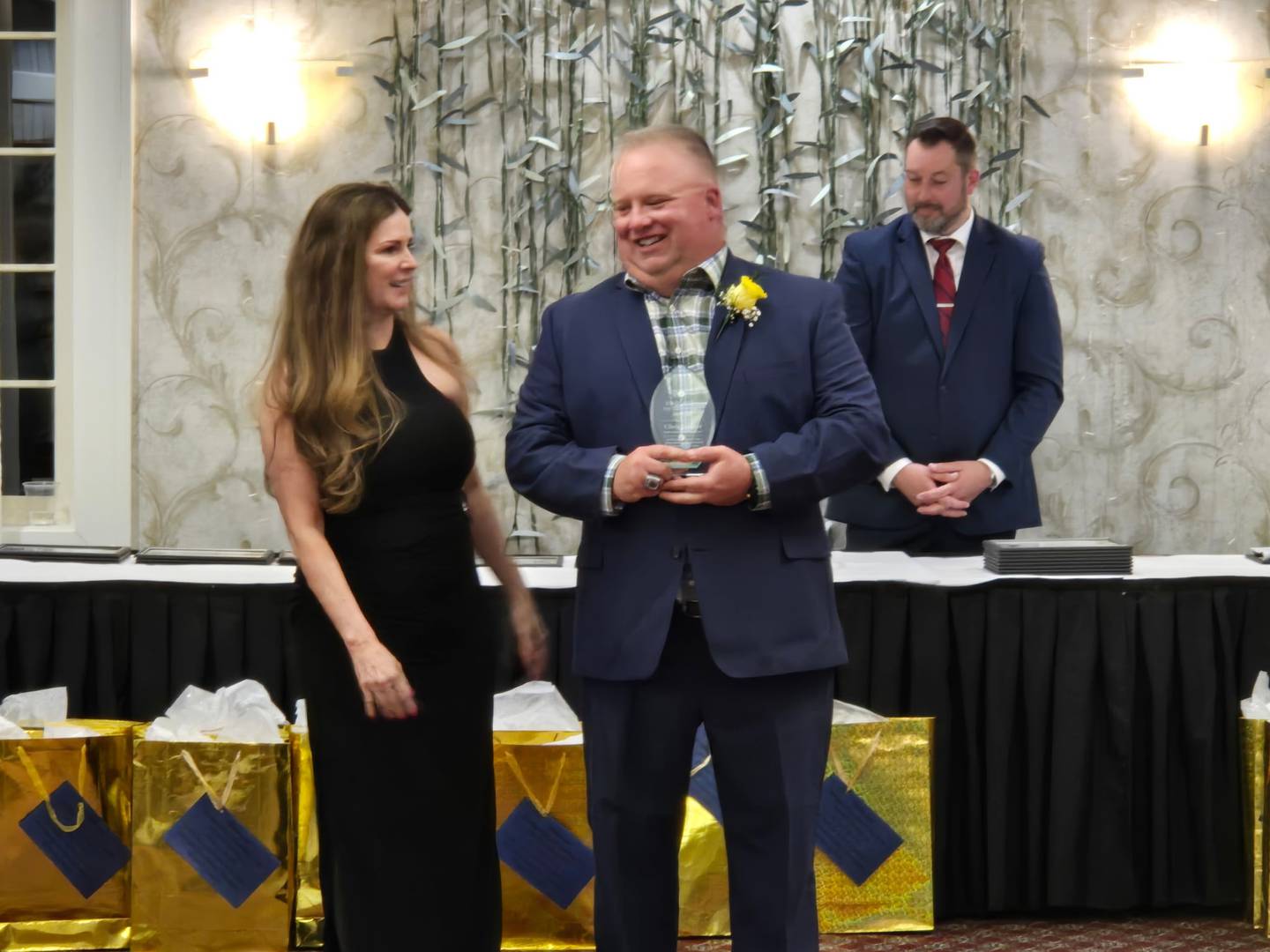 Chris Liggett, right, a paraprofessional and football coach at Cary-Grove High School, receives the non-certified staff of the year award from McHenry County Regional Superintendent of Education Diana Hartmann.