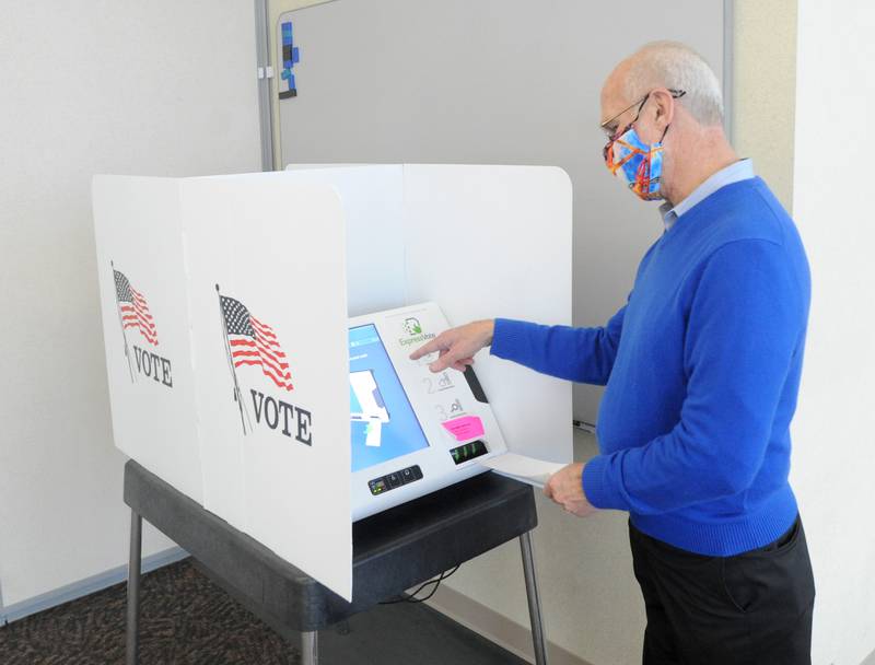 Election judge Randy Geisler explains the voting procedure and machine to a member of the media Saturday morning, Feb. 20, 2021, at the McHenry County Administration Building in Woodstock, during in-person early voting for the Feb. 23 consolidated primary.