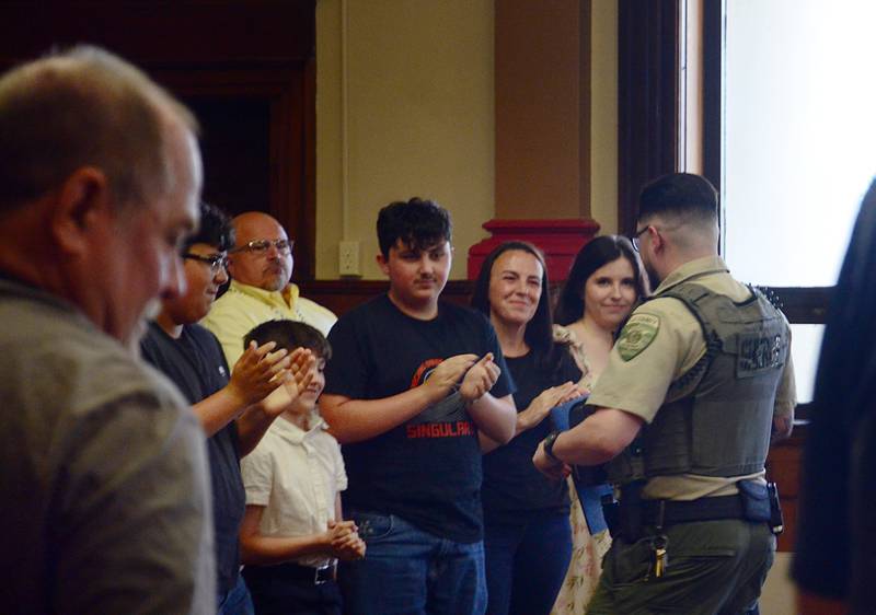 Attendees of the Lee County Board's meeting Thursday, April 23, 2026, clap for lifesaving award recipient Alejandro Castro (right).