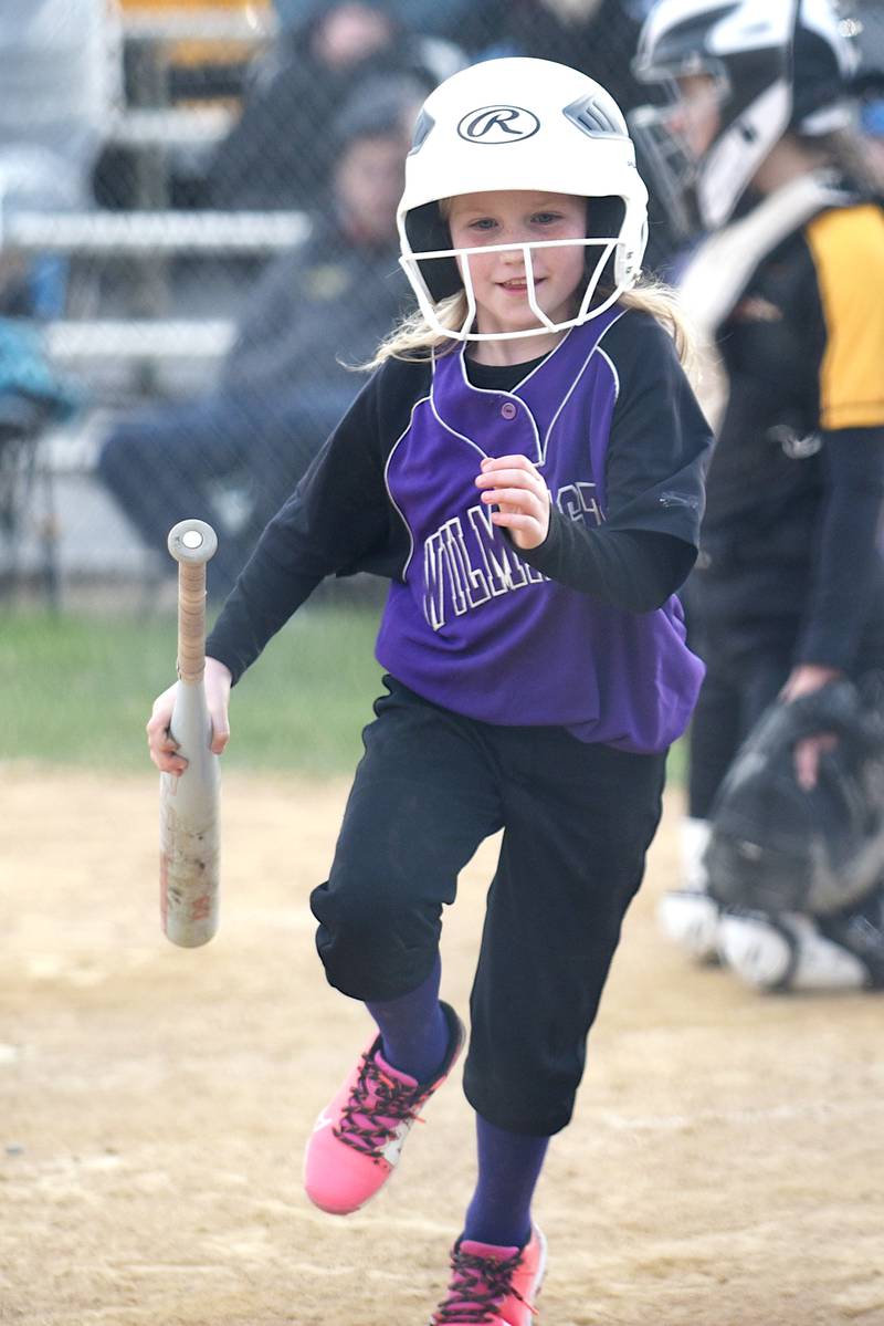 Wilmington softball bat girl Kelbie Niehls, 8, brings a bat back to the dugout during the Wildcats' home game against Herscher Tuesday, April 15, 2025.