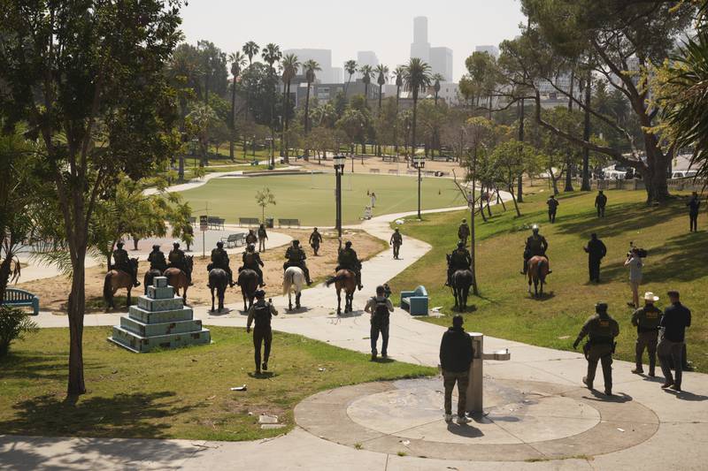 Federal agents ride on horseback at MacArthur Park, Monday, July 7, 2025, in Los Angeles. Their uniforms read "Police U.S. Border Patrol," and "HSI," which stands for Homeland Security Investigations. (AP Photo/Damian Dovarganes)