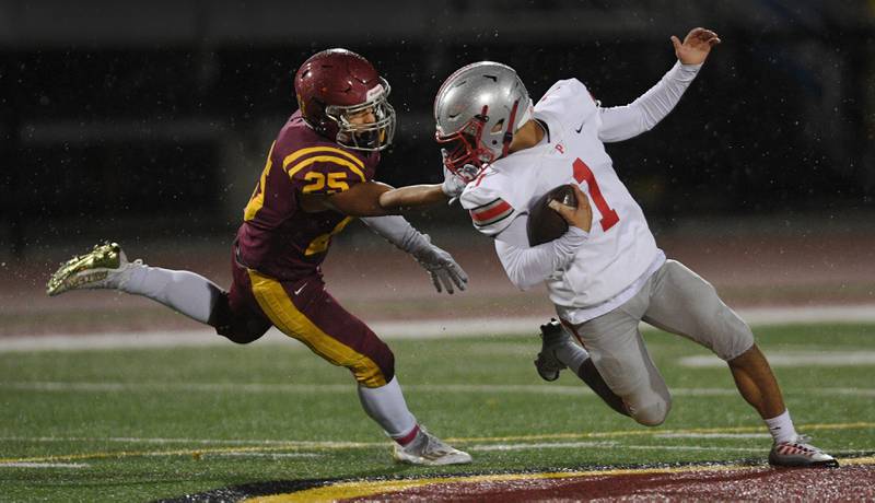 Schaumburg’s Dylan Kolasa gets the facemark of Palatine’s Rocco Paddack in a football game in Schaumburg on Friday, October 14, 2022.