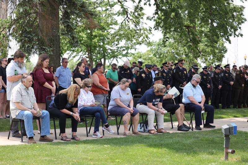 Officers bow their heads in a moment of silence alongside family and friends of fallen officers during the annual Law Enforcement Officers Memorial Ceremony honoring Kankakee County officers, held on the lawn of the Kankakee County Courthouse on Thursday, May 15, 2025.