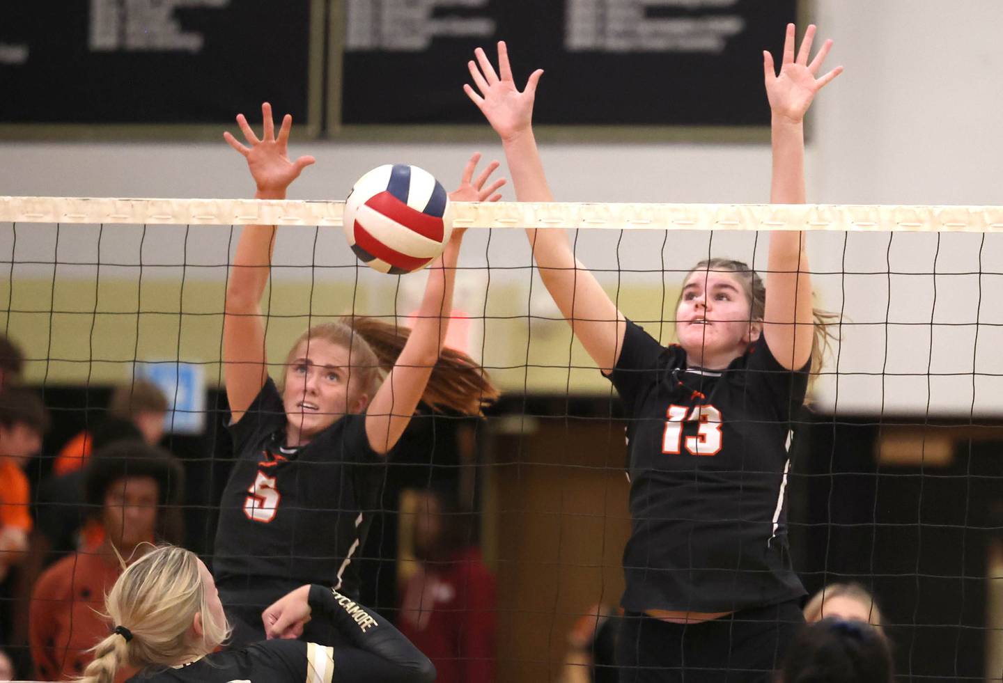 DeKalb's Hannah Mekjian (left) and Isabella Holiday try to block Sycamore's Jaycie Funderburg during their match Monday, Oct. 16, 2023, at Sycamore High School.