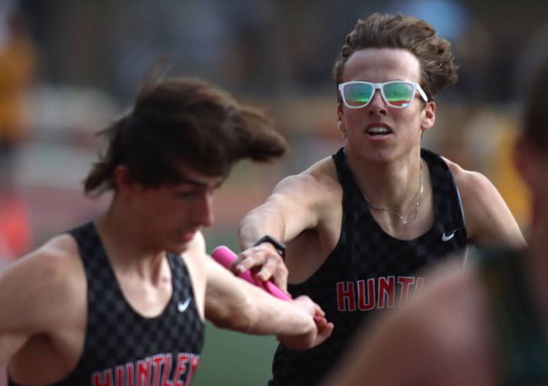 Huntley’s Logan Barreto, right, hands off to Mark Omoniyi in the 3200-meter relay in Fox Valley Conference boys track and field meet action at Huntley High School in Huntley on Thursday, May 15, 2025.