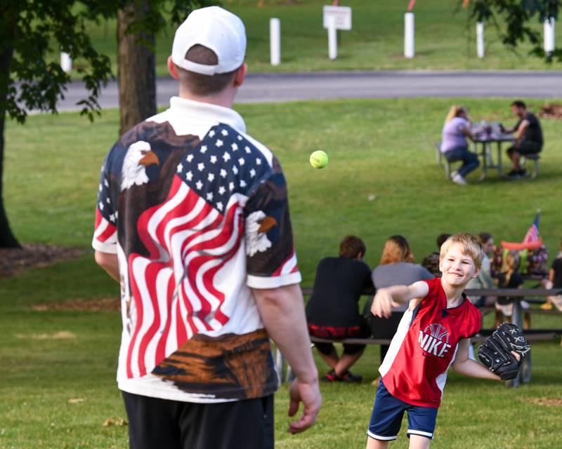Lyle Hinsch, 8, throws a tennis ball to his dad, Peter Hinsch of DeKalb, as they wait for fireworks to take place at Hopkins Park in DeKalb on Monday July 4, 2022.