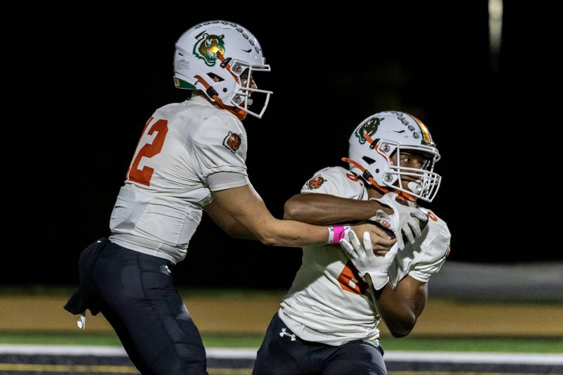 Plainfield East's Brady Cloherty hands-off the ball to David Croom during a varsity football game against Joliet West at Joliet West on Oct. 10, 2025.