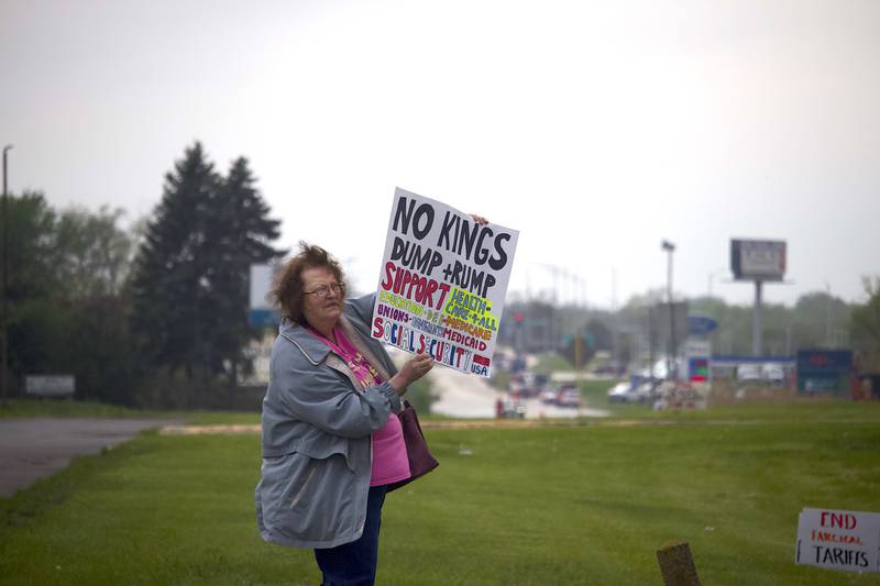 Linda Annen holds up a sign on Thursday, May 1, 2025, for a democracy rally in Joliet with signs critical of U.S. President Donald Trump. More than 20 people attended the rally that was held near the busy West Jefferson Street and the Joliet Regional Airport.
