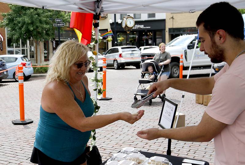 Karlee Stachura of McHenry receives a sample from Jacobite Tereza of Lots-A-Knots-Itialan Backery at the Tuesday Woodstock Farmer's Market on June 24, 2025, around the Historic Woodstock Square.
