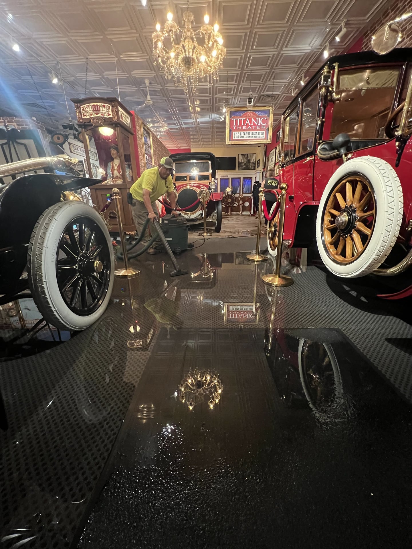 Antonio Zavala uses a wet vacuum to clean up water next to the 1912 Renault, famously known as the "Titanic Car," following an unexplained flooding incident at the Volo Museum.