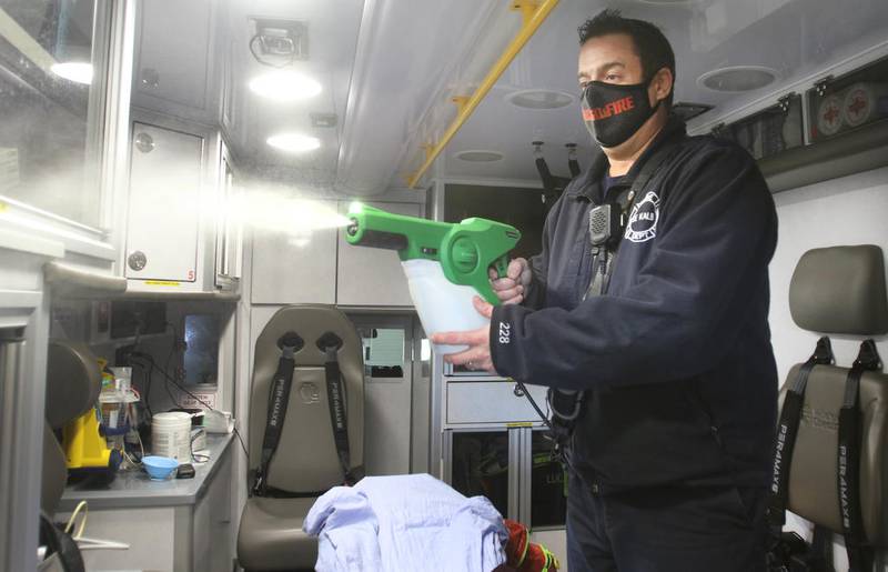 DeKalb firefighter/paramedic Pat Eriksen sanitizes the interior of an ambulance Wednesday, Dec. 2 at DeKalb Fire Station No. 1, with a new disinfectant sprayer the department recently acquired. Extra precautions and equipment have been necessary to keep fire department staff safe during the COVID-19 pandemic.