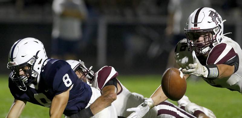 Prairie Ridge's Dominic Creatore tries to catch the ball as Cary-Grove's Andrew Prio is knocked to the ground by Prairie Ridge's Andrew Czarnecki during a Fox Valley Conference football game on Friday, Sept. 22, 2023, at Cary-Grove High School in Cary.
