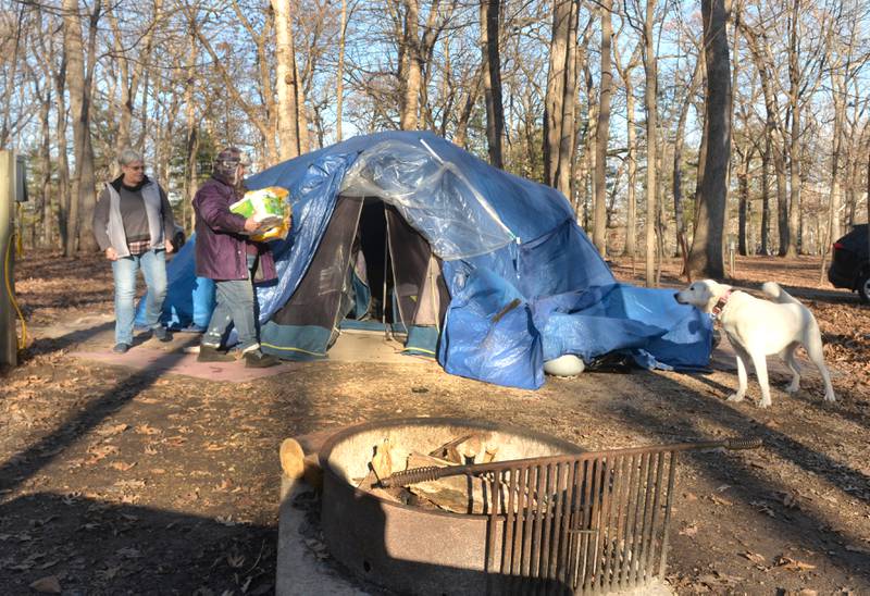 Barb Davis of Mount Morris (far left) brought paper towels and toilet paper to Sarah Wright (center) at her campsite in Lowden State Park on Thursday, Dec. 14, 2023. Wright was camping at Lowden and White Pines State Park through the summer months with her dog, Luna (right), after being without a home for several months. She is now camping at Lowden for the winter. Local residents have been helping Wright since reading about her plight on social media.