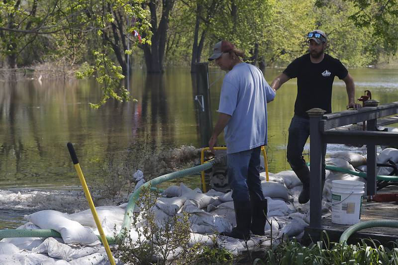 Volunteers work to protect a home in Holiday Hills  as flooding continues on the Fox River on Wednesday, April 22, 2026.
