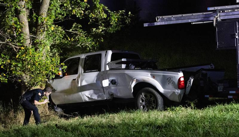 Around 9 p.m. Friday, Oct. 4, 2024, a Marseilles police officer searches under a crashed truck following a two vehicle crash. Multiple aluminum ladders secured to a large trailer connected to the pickup remained in place.