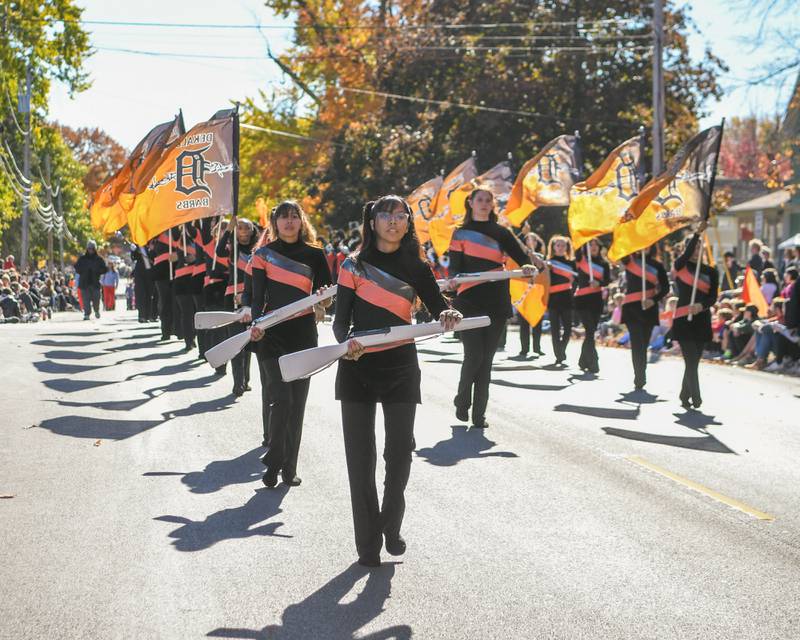 DeKalb High School's color guard leads the way as they perform along with DeKalb’s marching band during the Pumpkin Parade on Sunday Oct. 28, 2024, downtown at the 63rd annual Sycamore Pumpkin Festival.