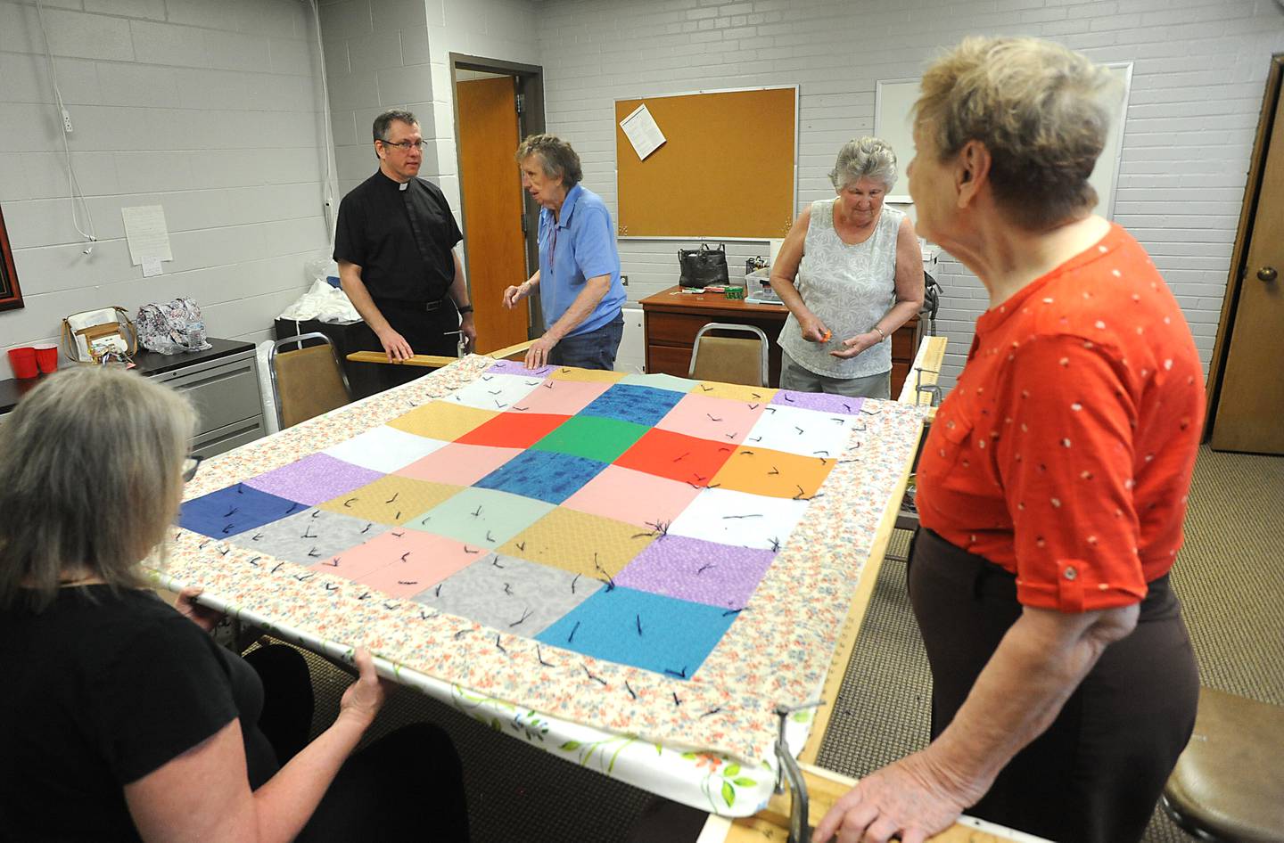 The Rev. Mark Beutow talks with quilters Wednesday, May 11, 2022, as they make a quilt to send to Lutheran World Relief in the basement of Zion Evangelical Lutheran Church and School, 4206 W. Elm St. in McHenry. Since January, with the quilters now able to meet in person again, they have made 11 quilts for people in need.