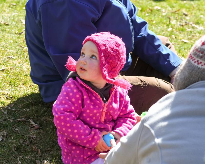 Ruby Doerfler, 2, of Cortland is all smiles after spotting the Easter Bunny behind her while she checks out the content of her eggs during the DeKalb Park District's annual children's egg hunt at Hopkins Park in DeKalb on Saturday, March 23, 2024.