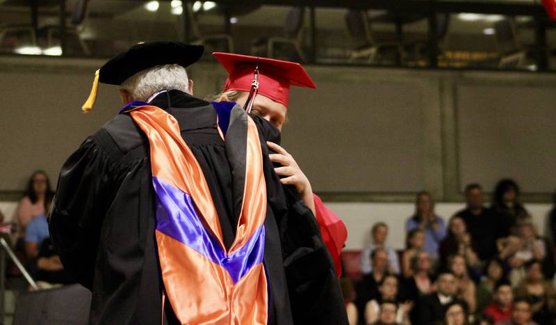 Sauk Valley Community College President David Hellmich embraces Olivia Costner, who gave a student address on Friday, May 12, 2023, during commencement. Costner graduated with high honors in the associate of arts. A high school senior, she will graduate from Amboy High School later this month.