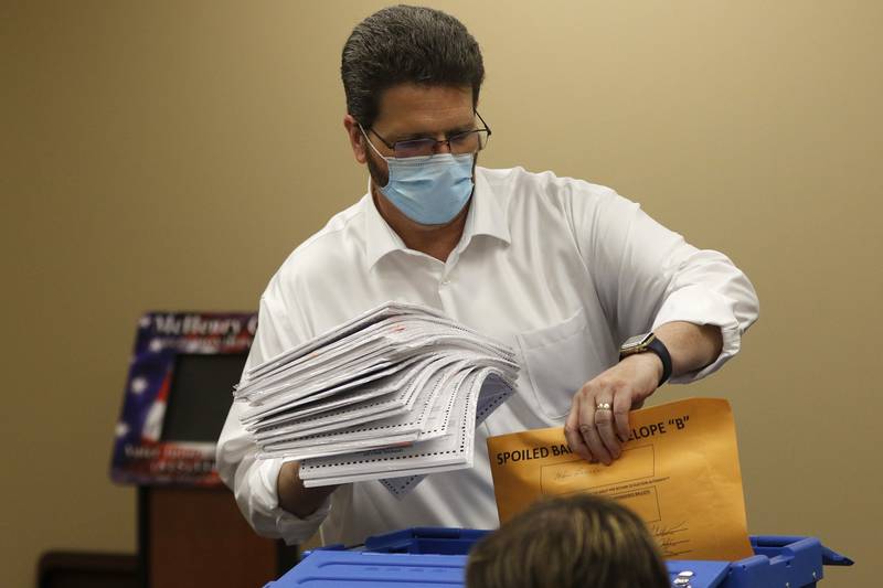 McHenry County Clerk Joe Tirio fills a secure blue bin with recounted paper ballots inside the voting tabulation room at the McHenry County Administrative Building on Thursday, April 8, 2021, in Woodstock.