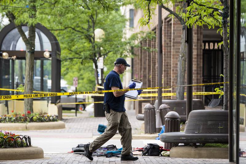 Members of the FBI's Evidence Response Team Unit investigate on Central Avenue near Green Bay Road in downtown Highland Park, Ill., less than 24 hours after a gunman killed several people and wounded dozens more by firing a high-powered rifle from a rooftop onto a crowd attending Highland Park's Fourth of July parade, Tuesday morning, July 5, 2022. (Ashlee Rezin/Chicago Sun-Times via AP)