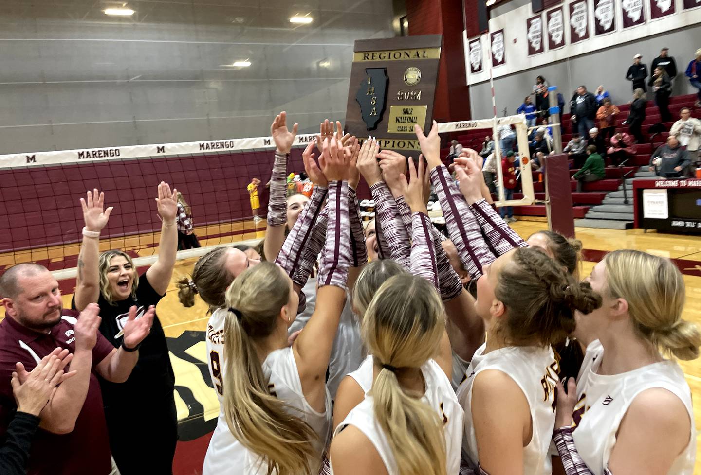 Head Coach Mike Kamholz, lower left, and the Richmond-Burton Rockets celebrate a two-set win over Genoa-Kingston in IHSA Class 2A Regional Title Game volleyball action on Thursday, Oct. 31, 2024, at  Marengo High School  in Marengo.