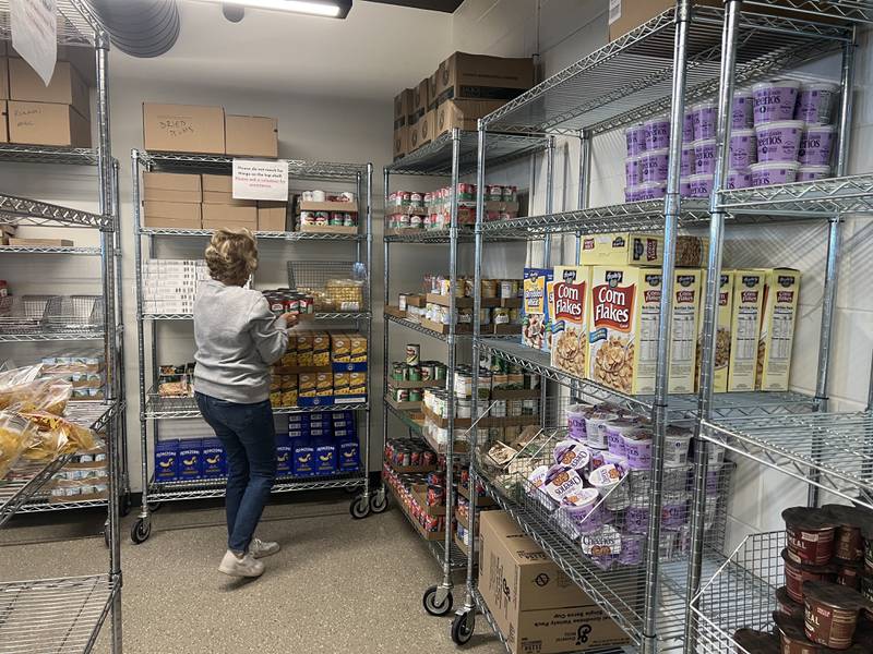 Linda Bugna, who's been volunteering for Rooted for Good for at least five years, stocks shelves at the Genoa Area Community Food Hub on March 25, 2025.