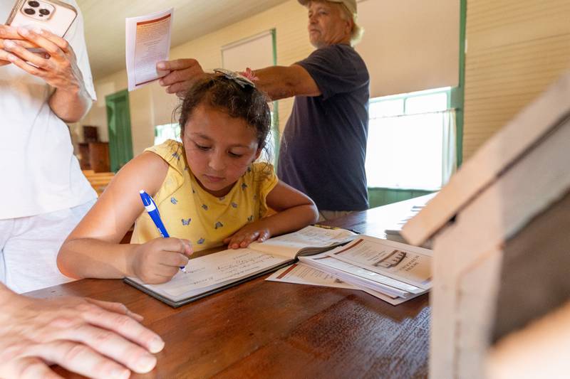 January Castillo writes in notebook on Saturday, August 9, 2025 at the annual Wenona Days on Chestnut Street in Wenona.