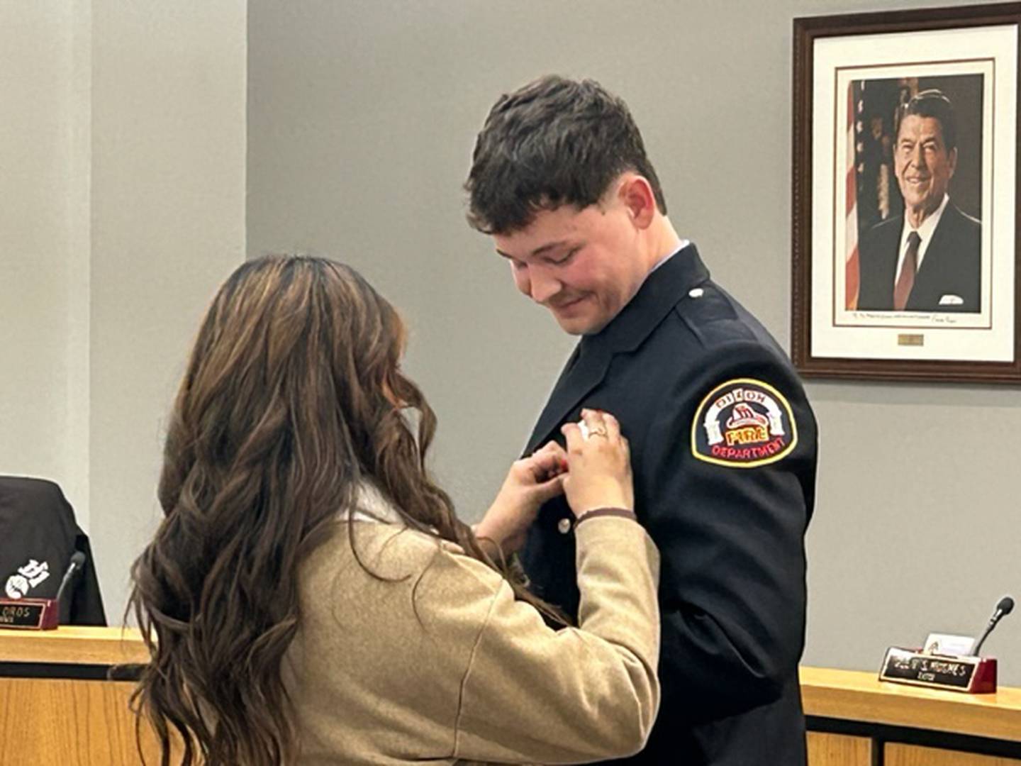 Evan Munson smiles as his firefighter badge is pinned on his jacket Monday at Dixon City Hall.