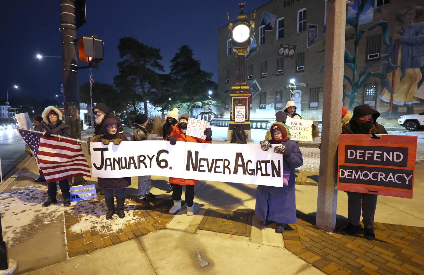 Members of Responsive Engagement Activating Civic Talent, along with or demonstrators hold their signs and wave at passing cars Friday, Jan. 6, 2023, during a Stand for Democracy demonstration at Memorial Park in downtown DeKalb. The second annual event was held to affirm the attendees commitment to American democracy.