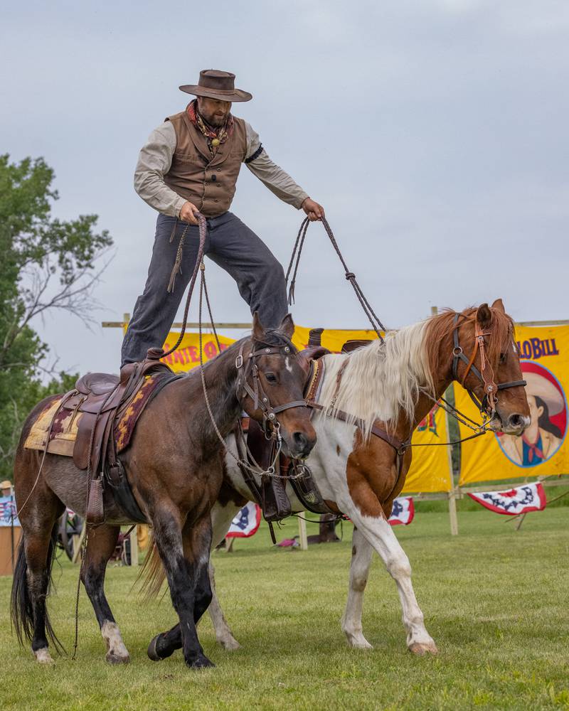 An actor in the Buffalo Bill's Wild West Extravaganza show rides two horses simultaneously during Wild Bill Days on May 31, 2025 at Jamie's Outpost in Utica.