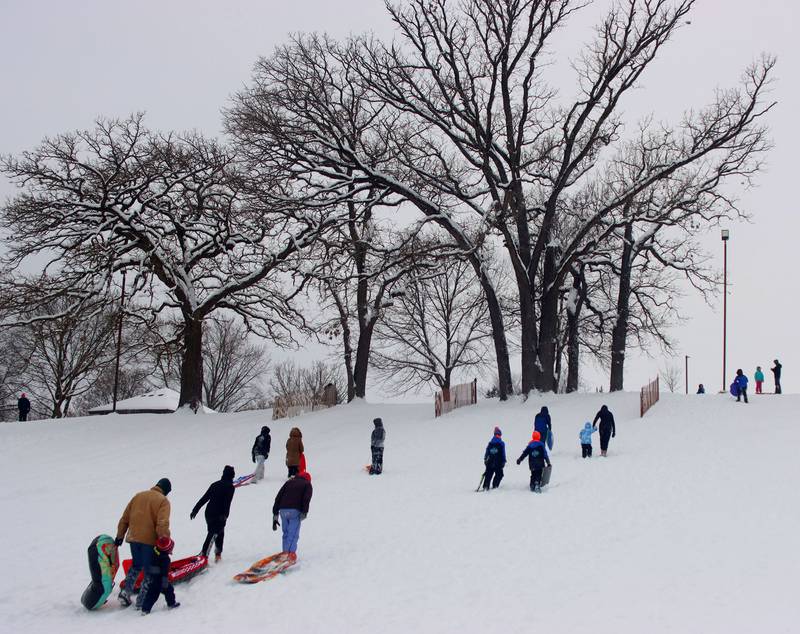 Sledders climb to the top of the hill at Veteran Acres on Sunday, Dec. 7, 2025 in Crystal Lake.