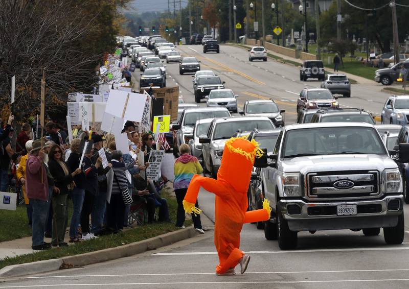 A protester walks across Route 31 during a "No Kings” protest rally on Saturday, Oct. 18, 2025, in McHenry. The protest drew thousands of protesters to the area to protest the policies of President Donald Trump.