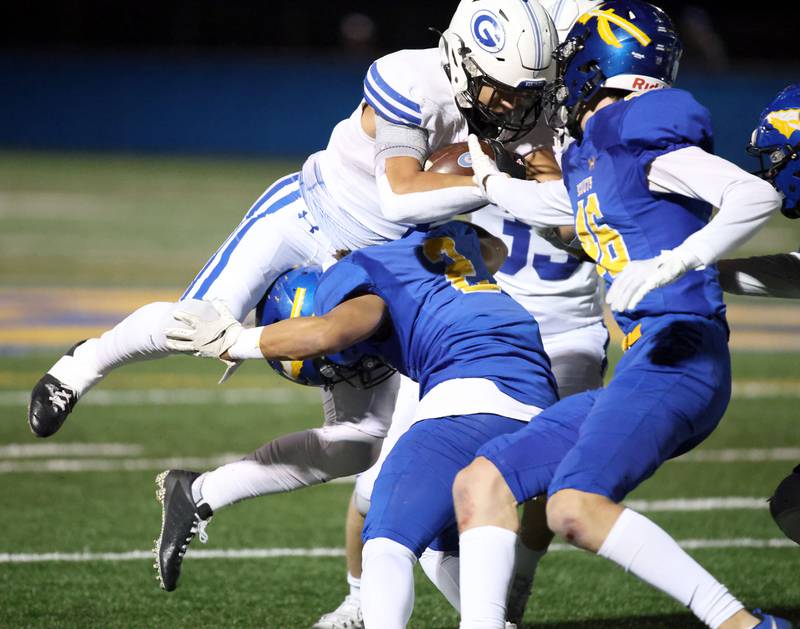 Geneva's Troy Velez (4) goes airborne as he is hit by Lake Forest's Nathan Williams (2) during the IHSA Class 6A playoff game Friday November 3, 2023 in Lake Forest.