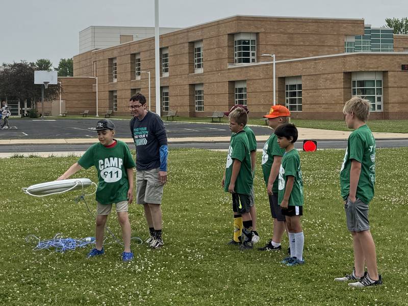 A Camp 911 kid learns how to properly throw a life preserver into the water.