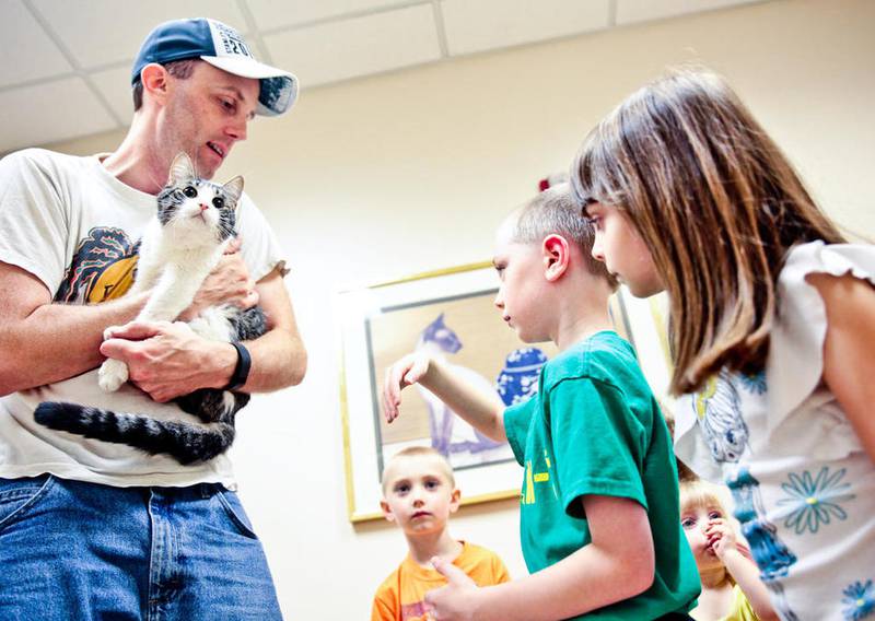 Dave Rosengarden explains to his children (left to right,) 5-year-old Judson, 8-year-old Jeremy, 18-month-old Myra and 7-year-old McKayla, the proper way to hold their new cat, Ray, as they proceed with adopting him Saturday, July 23, 2016, from the McHenry County Animal Control during the national Clear the Shelter event.