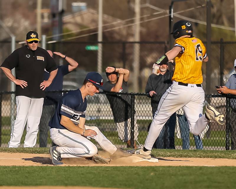 Oswego East's Zach Polubinski (8) fields a throw a first for the out during varsity baseball game between Oswego East at Joliet West.  April 10, 2023.