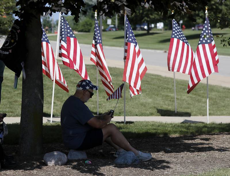 Ron Sloan of McHenry, checks his phone as he waits for a group of veterans returning from an Honor Flight trip to Washington D.C., on Sunday, Aug. 27, 2023.