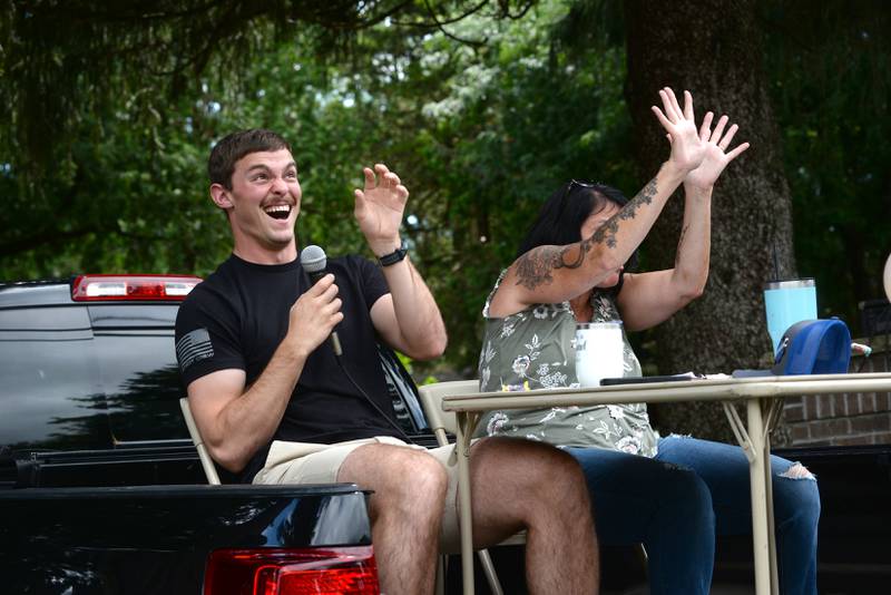 German Valley Days parade announcers Hunter Rogers and Christine Gentry fend off pieces of candy thrown by a German Valley youth baseball team during the parade on Saturday, July 19, 2025.