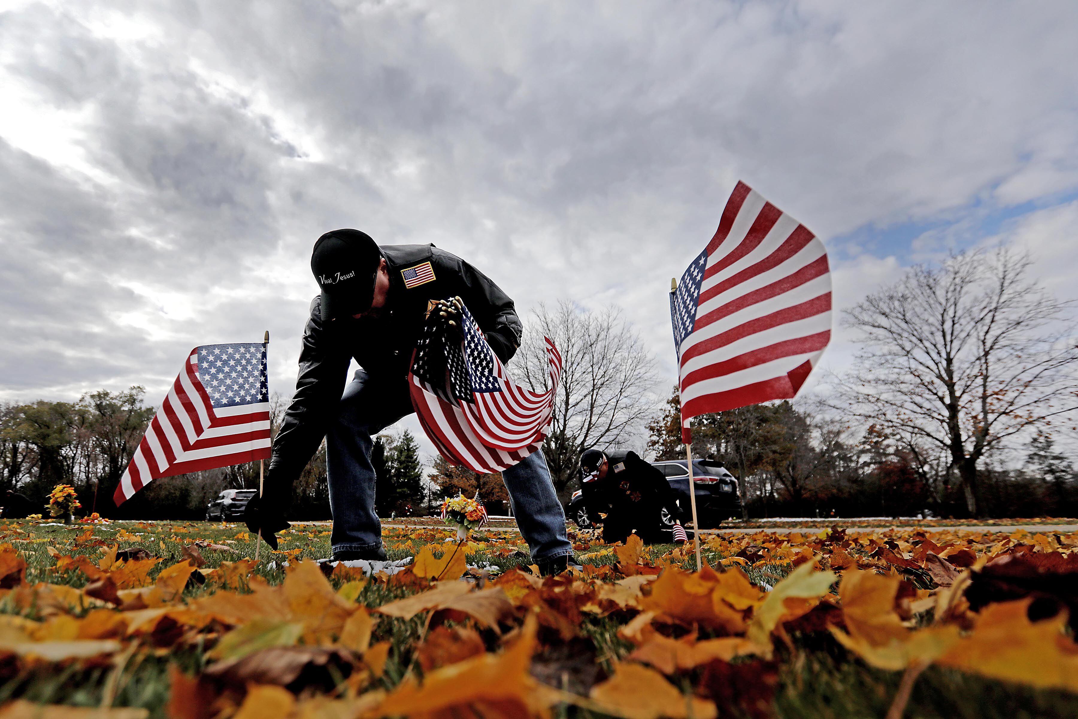 Mark Kuczera places flags during the Veterans Day flag placement ceremony Tuesday, Nov. 11, 2025, at the gravesites of veterans at McHenry County Memorial Park Cemetery in Woodstock. Members of the Knights of Columbus Patriotic 4th Degree from the Bishop Boylan Assembly placed American Flags at nearly 140 veterans' grave markers.