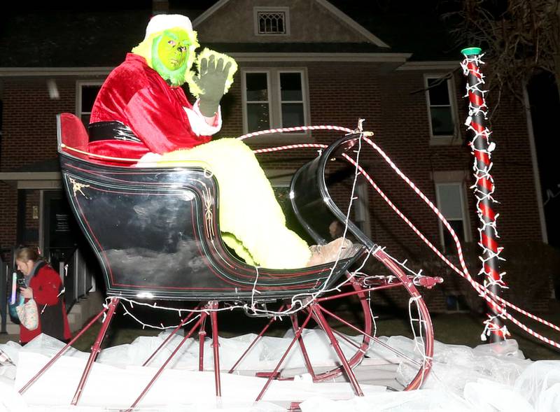 The Grinch waves on top of a float during the annual Christmas Parade on Saturday, Dec. 7, 2024 on Peoria Street in Peru.