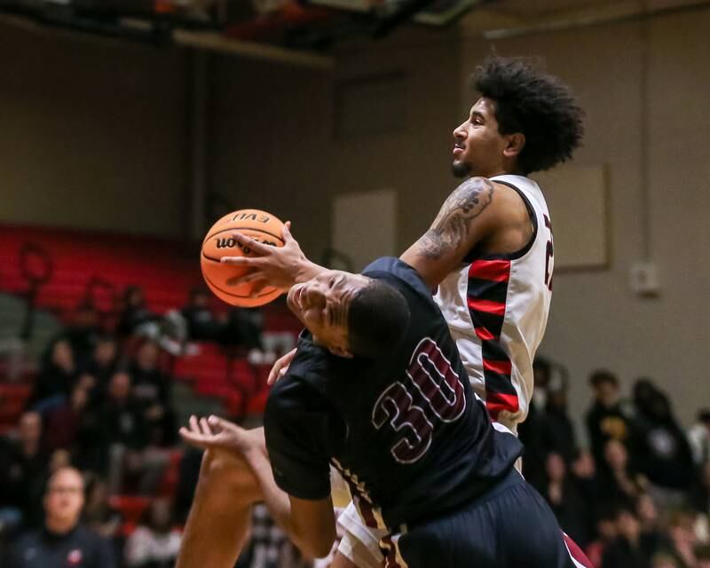 Plainfield North's Pierre Pointer (30) tries to draw a charge from Bolingbrook's Joshua Pettigrew (22) during their basketball game between Plainfield North at Bolingbrook, Friday Dec 13, 2024 in Bolingbrook.