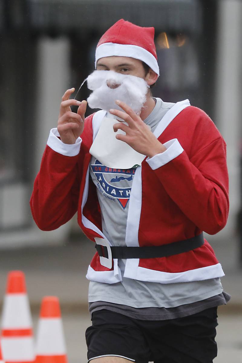 Carel Lamprecht puts his Santa beard back on as he runs to the finish line during the McHenry County Santa Run For Kids on Sunday morning, Dec. 3, 2023, in Downtown Crystal Lake. The annual event raises money for agencies in our county who work with children in need.