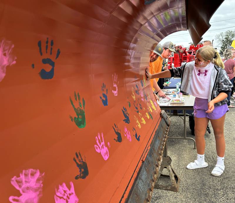 Taylor Stacy, 12, of Byron, puts her painted hand on the blade of an Oregon snow plow at the Oregon Police Department's  National Night Out at River's Edge Experience in Oregon on Tuesday, Aug. 6, 2024. The event was co-hosted by the Oregon Park District.