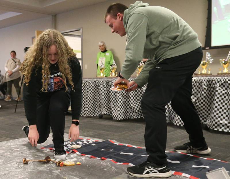 Ottawa Township High School students Christian Gran and Keagan Gromm pick up pieces of their cheeseburger car during the 18th annual Editable Car Contest on Wednesday, Feb. 28, 2024 at Illinois Valley Community College in Oglesby.