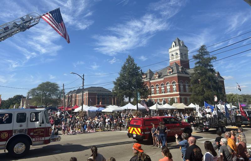 Sunny skies and hot temperatures greeted visitors to the Harvest Time Parade held during Autumn on Parade on Sunday, Oct. 5, 2025 in Oregon. Here, the Oregon Fire Department raises an American flag for the national anthem in front of the parade-viewing stand on South Fourth Street.