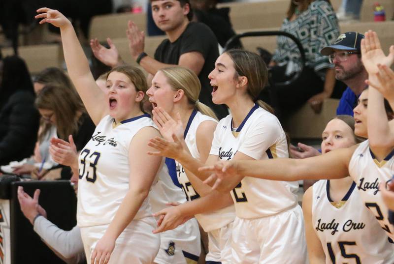 Members of the Marquette girls basketball team react after Kaitlyn Davis sinks a three-point basket over Peoria Manual during the Falcon-Irish Thanksgiving Tournament on Monday, Nov. 18, 2024 at Flanagan High School.