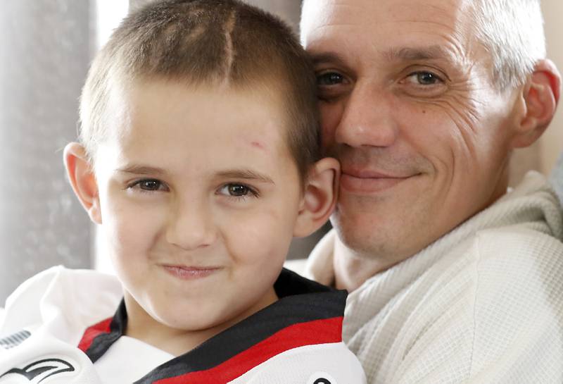 Alex Moscrip, 7, son of Brad and Aleksandra, with his dad on Wednesday. Nov 13, 2024 at his home in McHenry Township. Hewas hit by a car in July and left with traumatic brain injury and is now recovering at home.