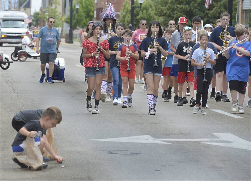 The Streator Grade School Band marches down Main Street as children work to pick up candy from the previous float Sunday, July 2, 2023, during the Independence Day parade in downtown Streator.